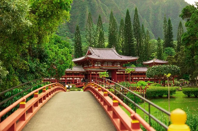 Eine rote Brücke führt zum Byodo-In-Tempel unterhalb bewaldeter Berge