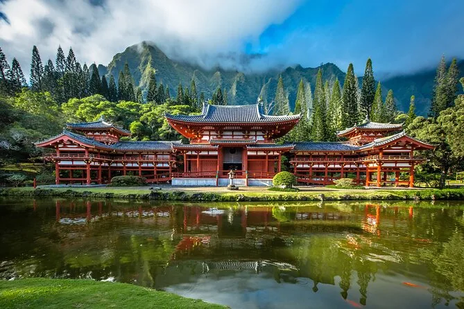 The red Byodo-In Temple reflected in its pond below green mountains